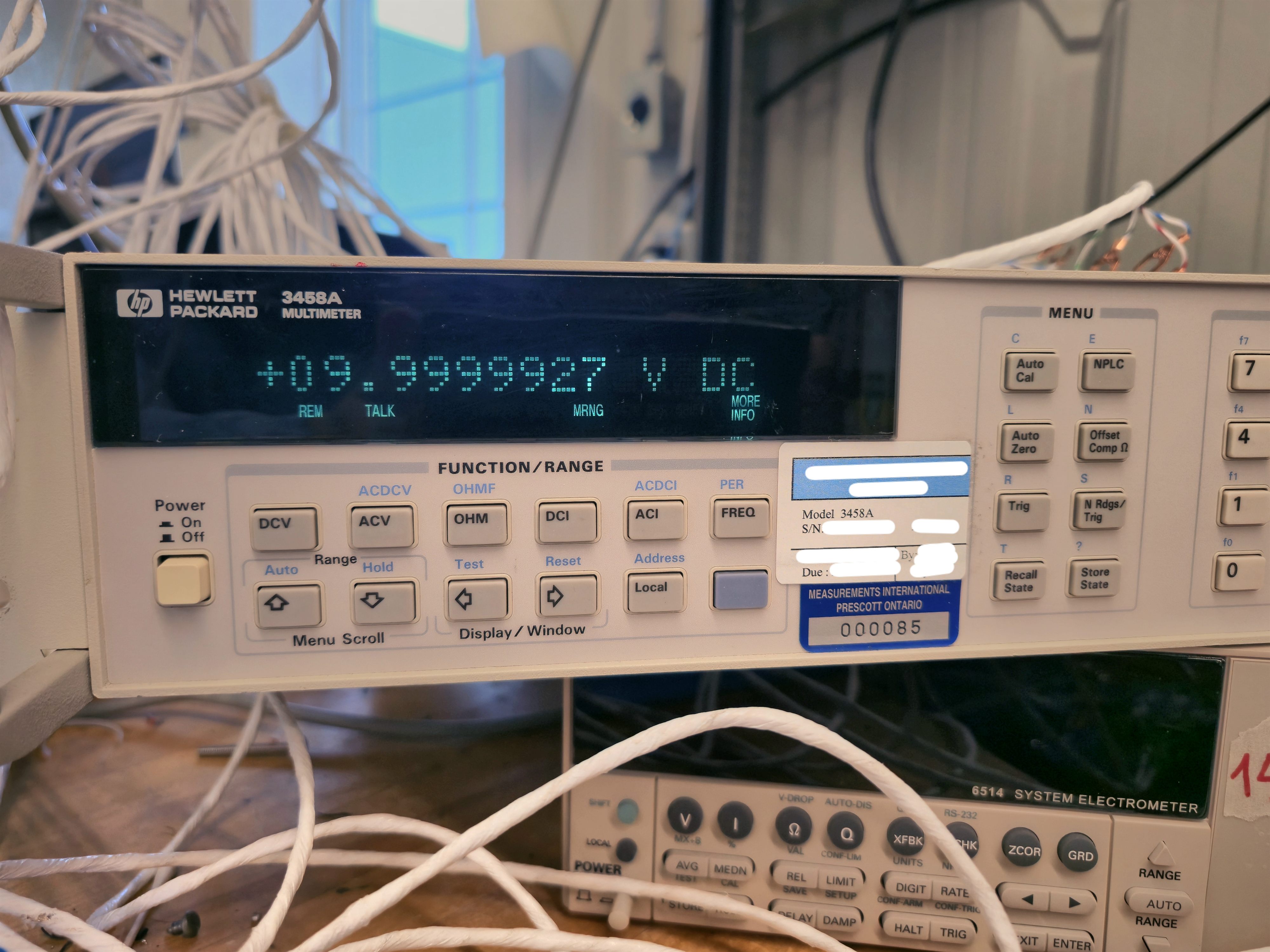 An HP 3458A 8½-digit multimeter reading 9.9999927 volts DC at the reference output