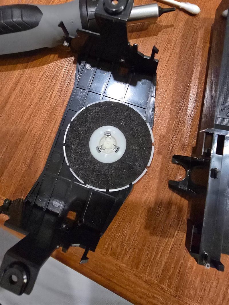Removed plastic disc clamp assembly from a Sony CD mechanism showing its felt disc-contact surface